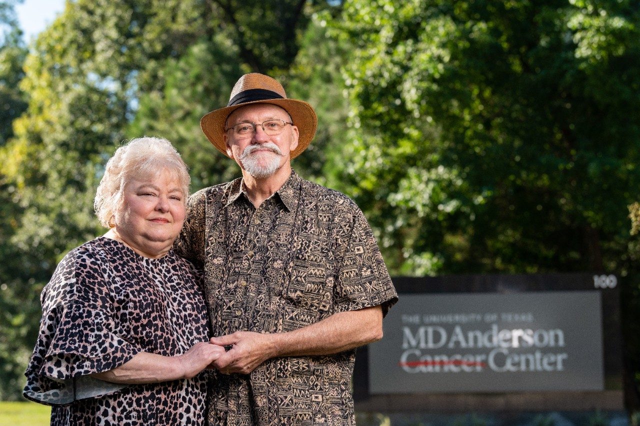 乳腺癌生存者Teresa和Billy Mayo站在MDAnderson癌症中心标志旁举手