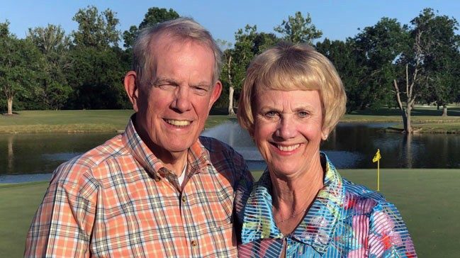 Jim和Carolyn无人机在高尔夫球场上笑并肩并肩站立