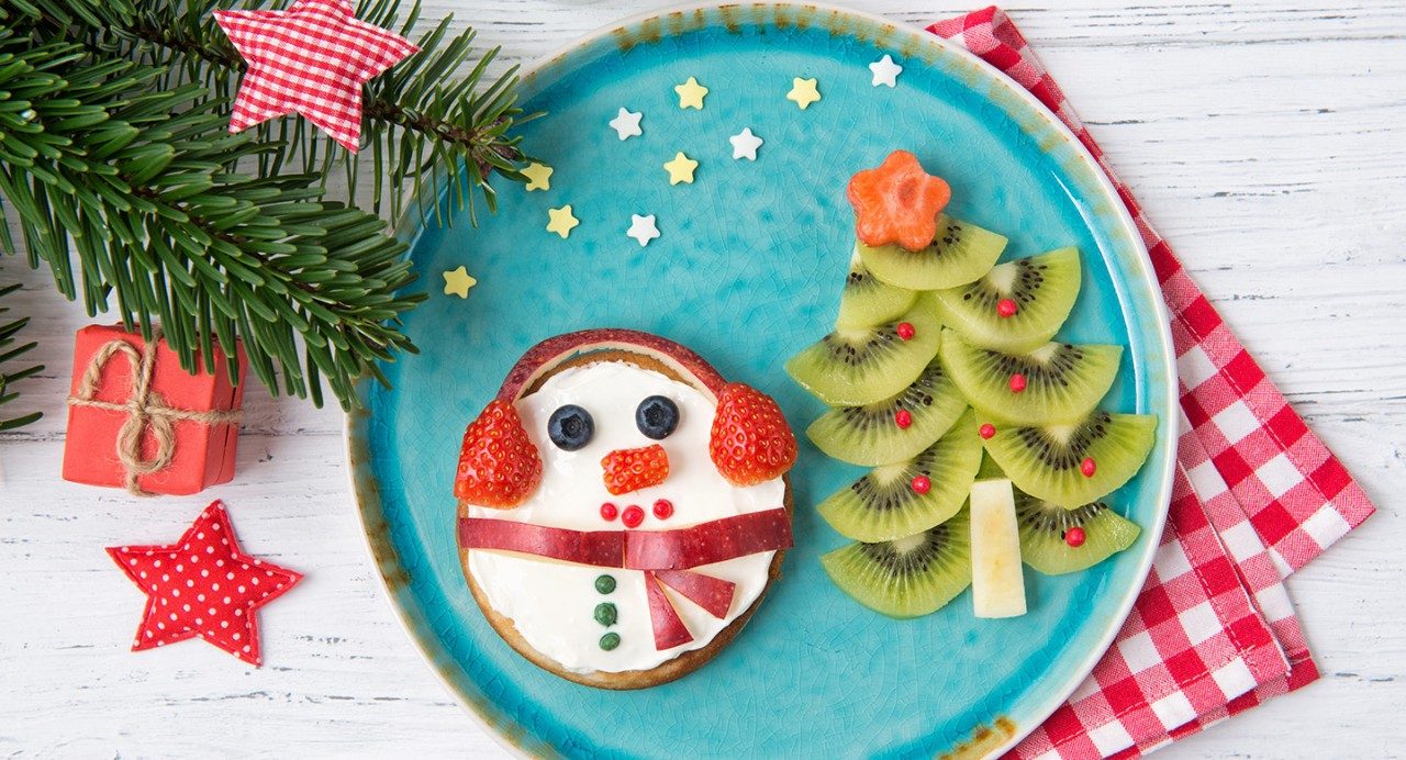 假日板显示雪人饼干和猕猴桃切片在节日树的形状。