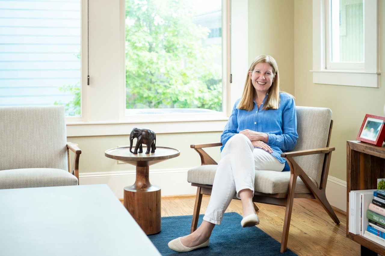 凯萨琳Schmeler,医学博士坐在桌子旁边的椅子上,一头大象雕塑。