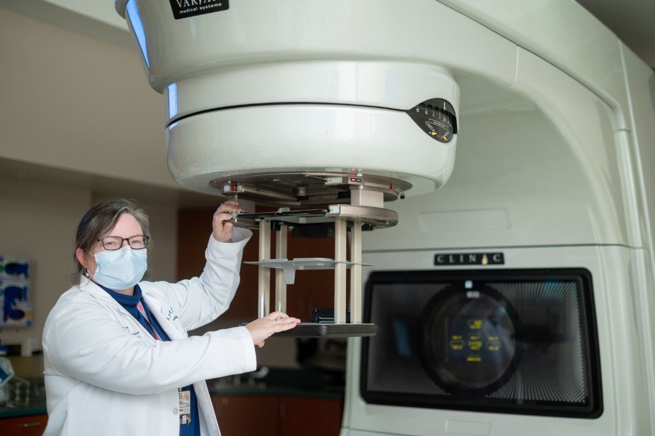 温迪·伍德沃德,医学博士博士,站一个放疗机。