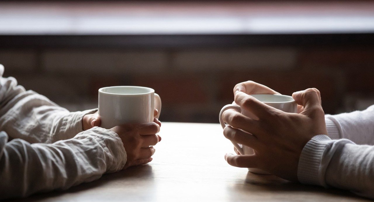 股票的照片两套手抱着咖啡杯放在桌上,彼此对面
