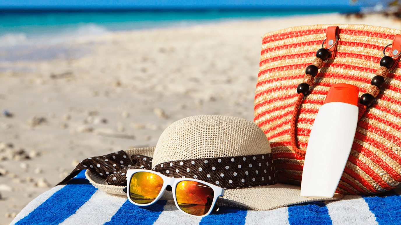 帽子、太阳镜和沙滩包放在沙滩上的毛巾上